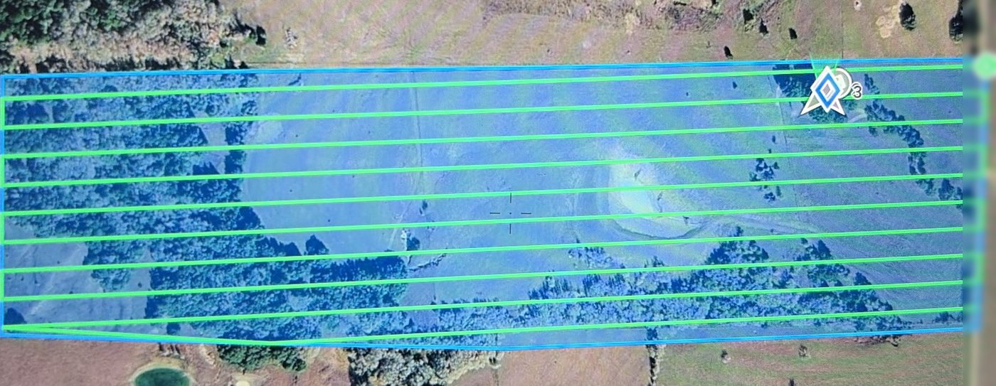 Aerial view of a pasture with a planned grid of parallel drone flight lines drawn across it